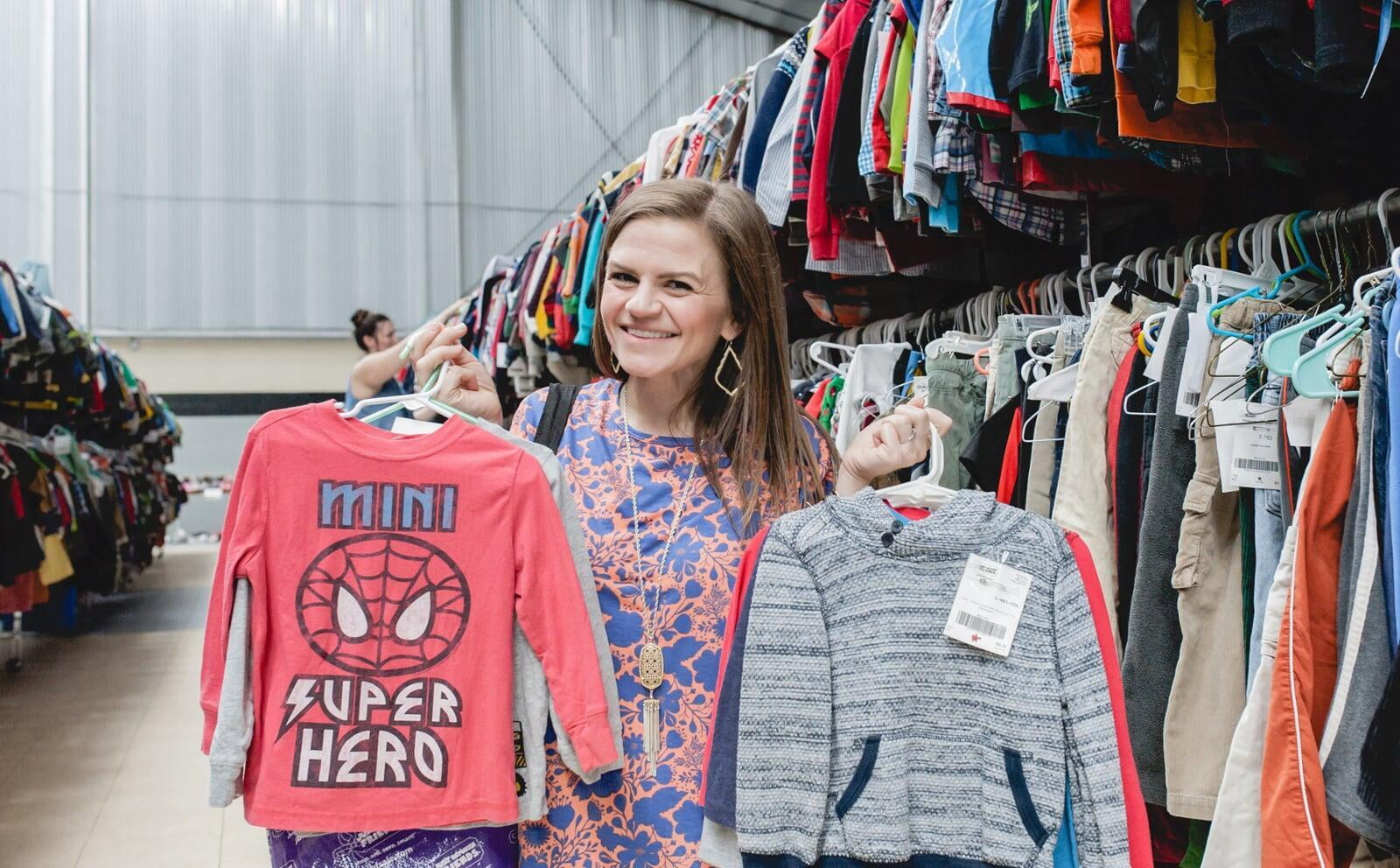 A woman wearing a face mask stands between rows of toys at the sale.